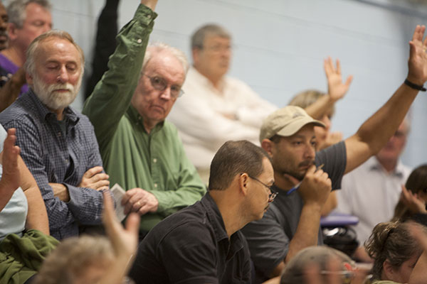 People raising hands at a community meeting