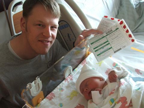 2015-16 Management Certificate program scholar John Thompson holding his baby's newborn screening paperwork.