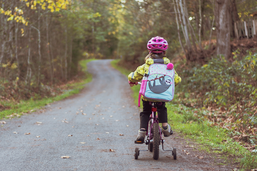 A young girl rides a bicycle on a quiet country road