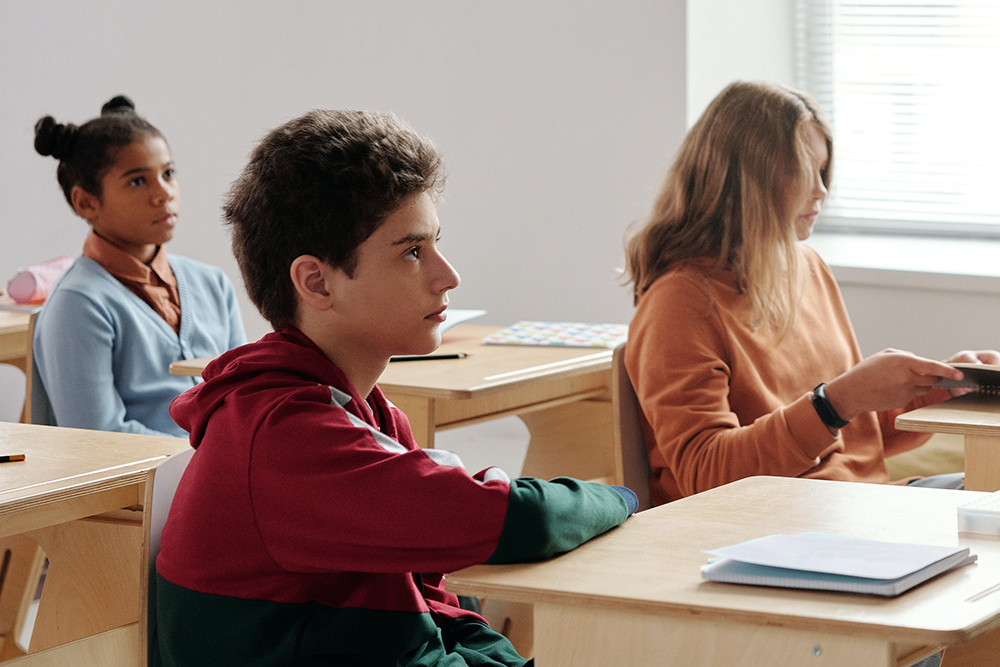 Photograph of young teen students at desks in a classroom.