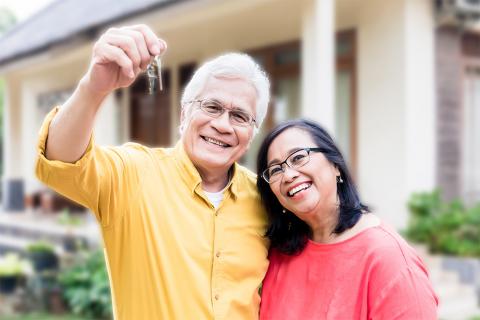 Photo of a man and woman in front of a house, with the man holding the keys