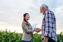 Photo of two people shaking hands outside on a farm