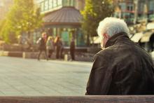 Elderly person looking down with back turned to camera