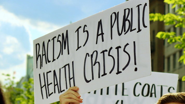 Photograph of a sign reading "Racism is a public health crisis!"