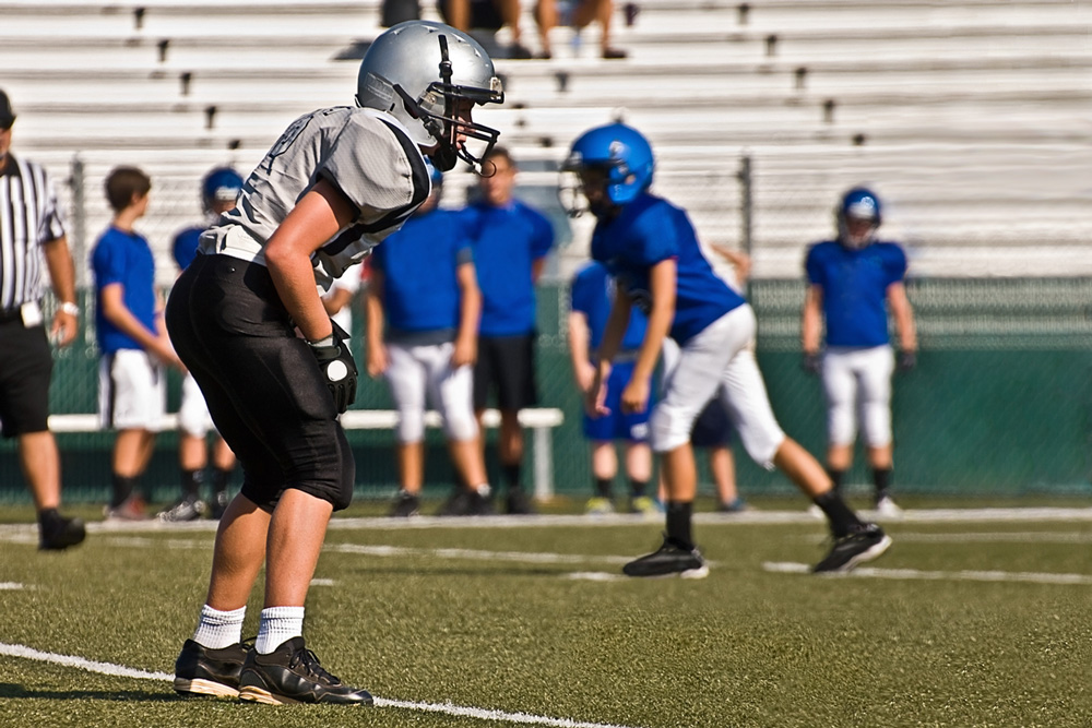 Photograph of a teen football player on the practice field.
