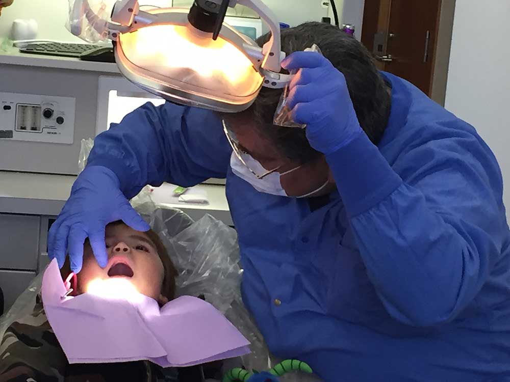 Photograph of a dental health aid therapist examining a patient.