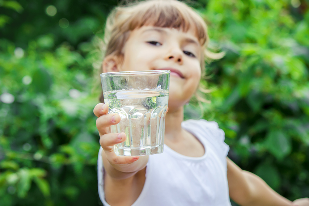 Photograph of a girl holding a glass of water.