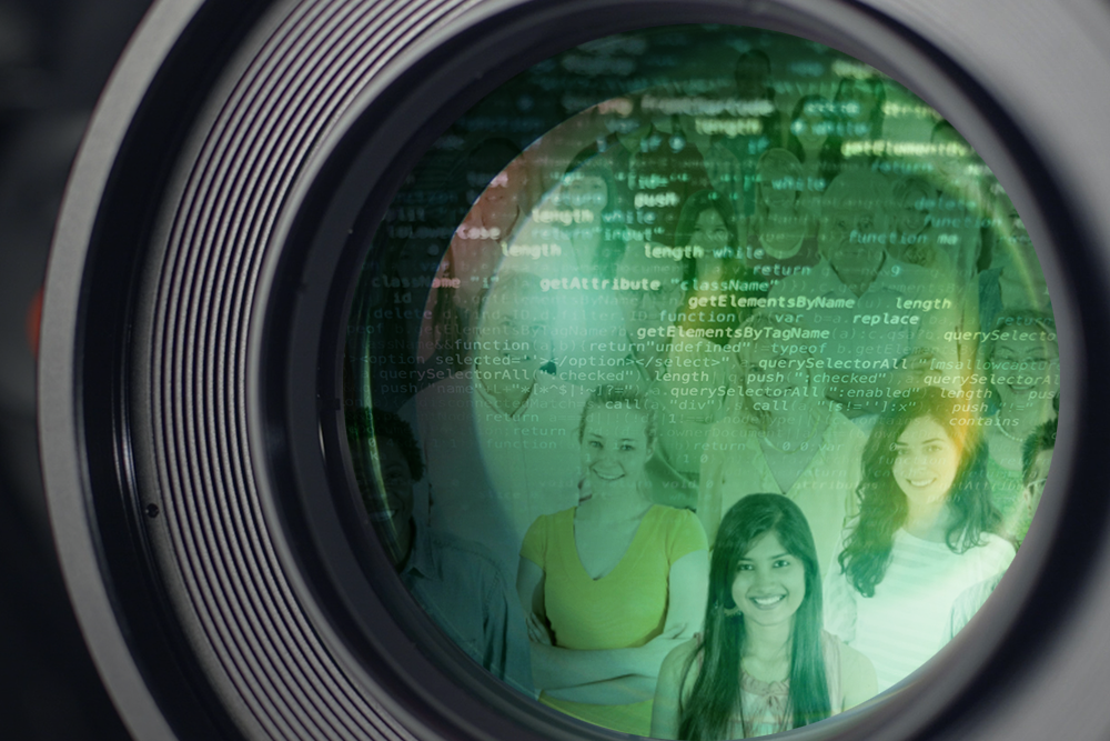 Close up view of green camera lens reflecting a crowd and computer code