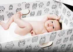 Photograph of a baby laying in a "baby box."