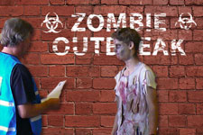 Photograph of exercise staff with made-up actor superimposed over a "zombie outbreak" sign.