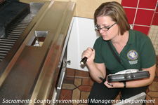 Photograph of a restaurant inspector looking under a counter.