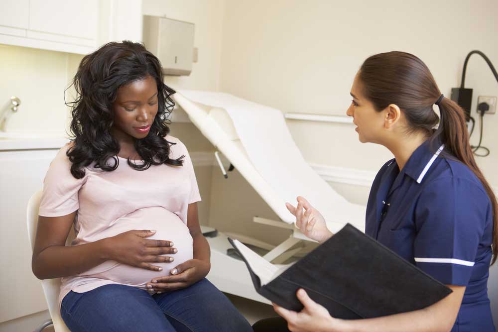 Photograph of a pregnant woman consulting with a health care provider.
